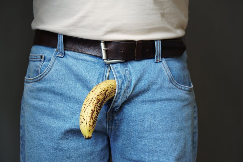 old limp drooping banana hanging from genital area of clothed unrecognizable man, impotence erectile dysfunction (ed) or limp-dick concept